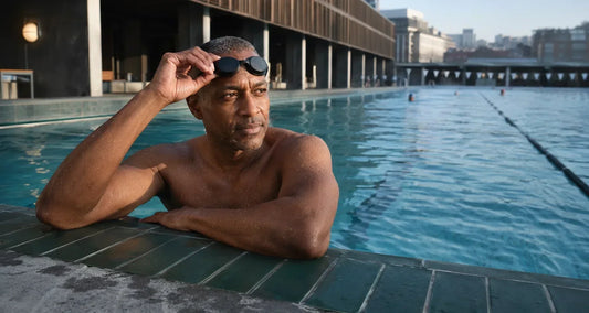 Man pausing at the edge of an outdoor pool after an early-morning swim