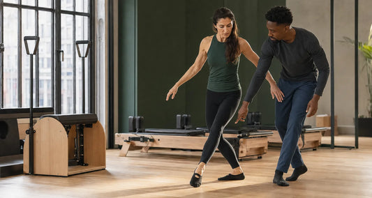 Woman refining a ballet-inspired movement sequence with a coach in a contemporary Milan studio