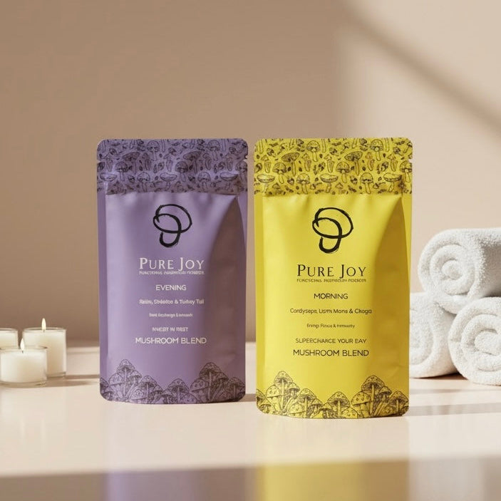 Two packages of Pure Joy mushroom blend on a table with candles and towels in the background.