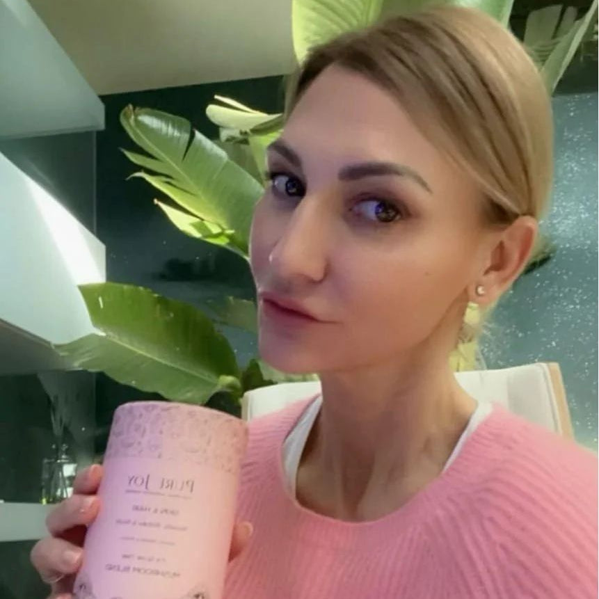 Woman holding a pink container with green plants in the background